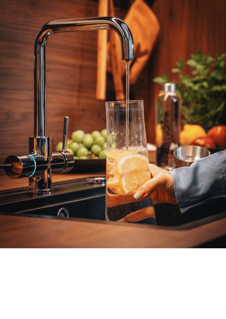 WELLQ® Wassersystem füllt ein Glas mit Wasser und Zitrone
