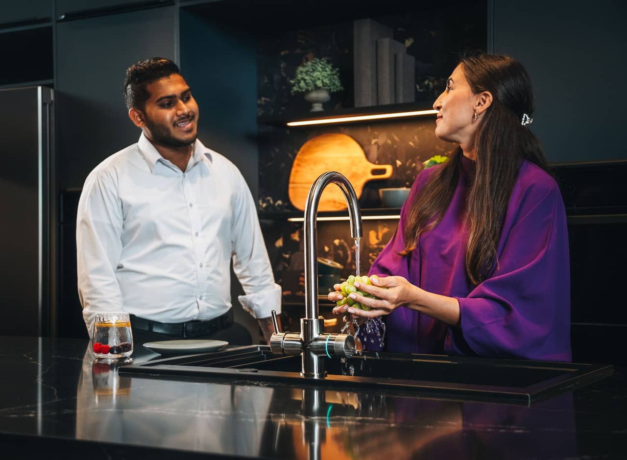 Couple enjoying filtered water from the WELLQ kitchen tap in a modern Dubai kitchen